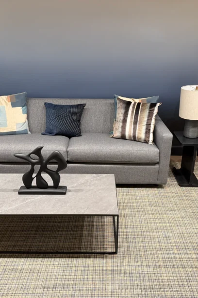 Gray sofa and glass coffee table against a blue-gray wall in Cambridge Lounge.