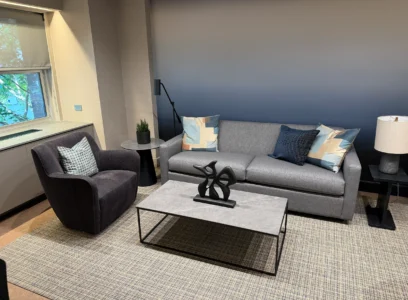 Gray sofa and armchair arranged around a glass coffee table in Cambridge Lounge.