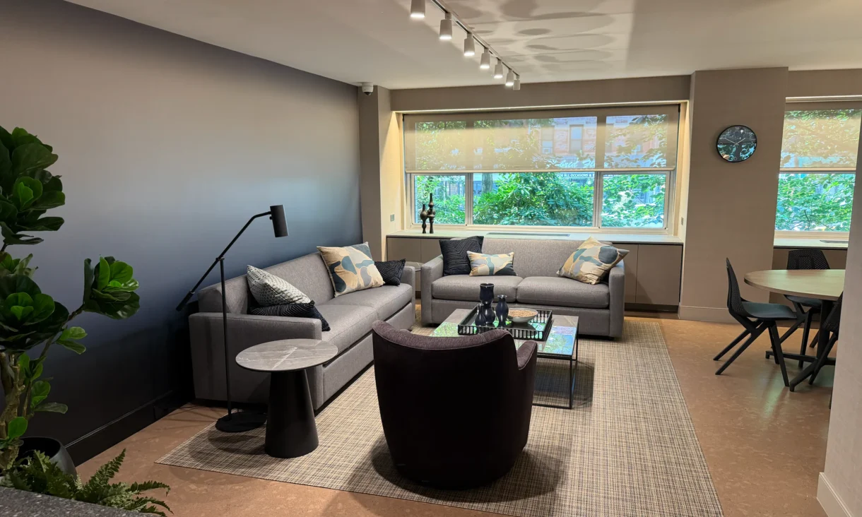 Cambridge Lounge seating area beneath track lighting, with sofas and armchairs beside a window.