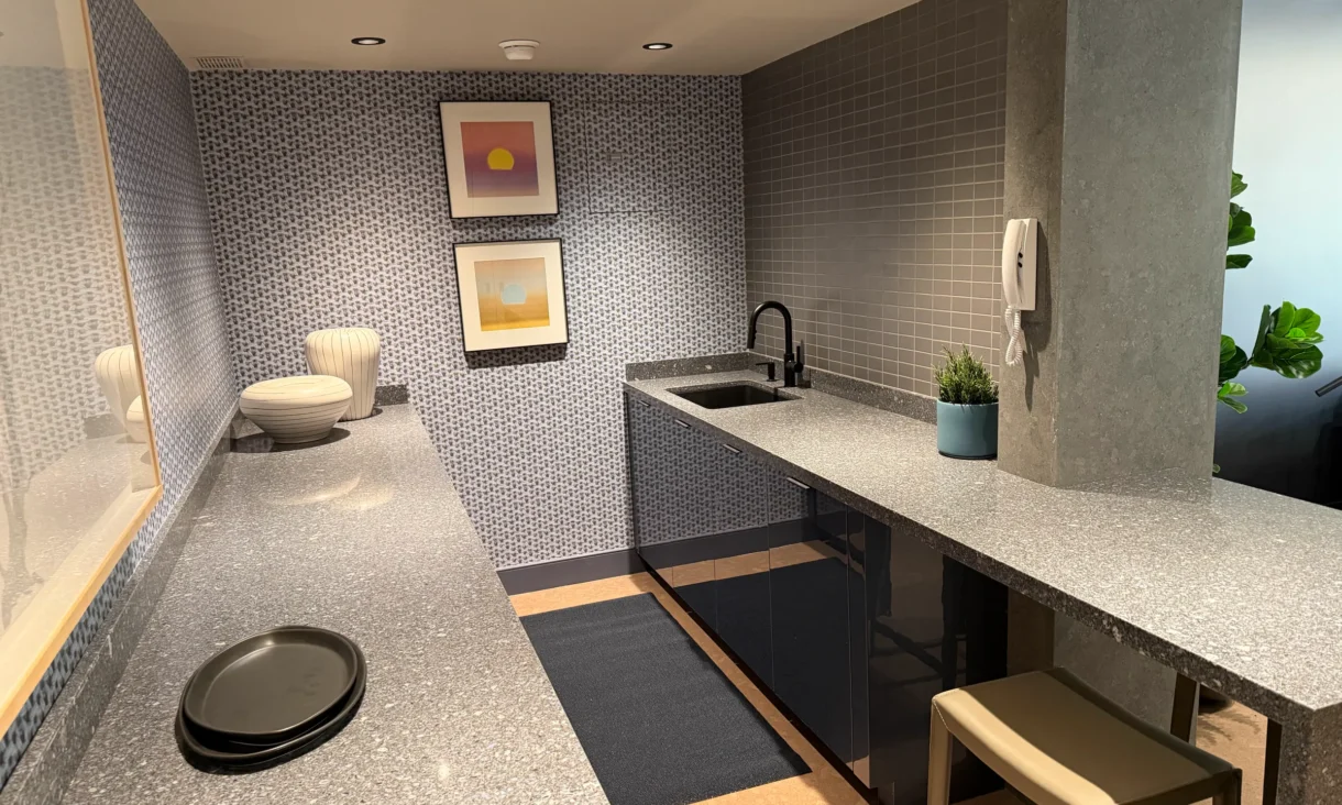 Cambridge Lounge kitchenette with stone countertops, dark cabinetry, and a small counter stool.