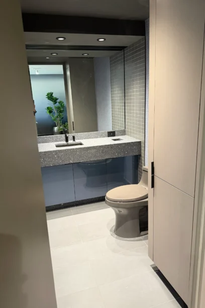 Cambridge Lounge restroom with a wide mirror, stone vanity, and toilet.