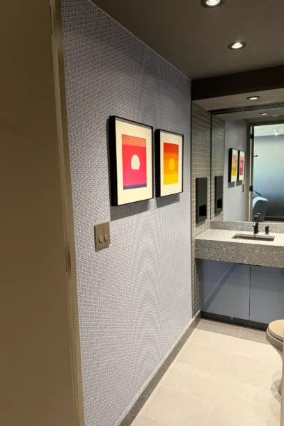 Hallway with framed artwork leading to the Cambridge Lounge restroom.